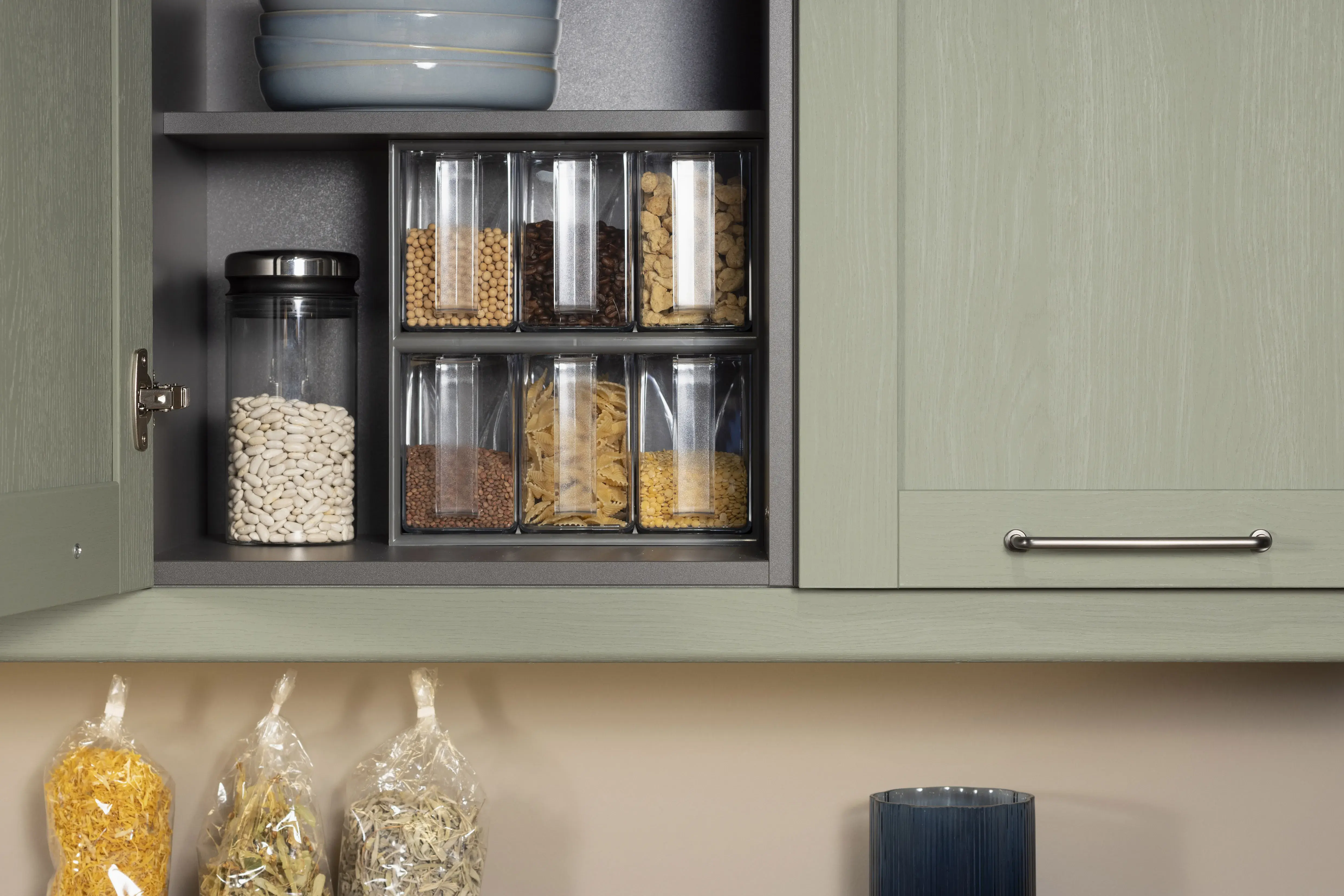 Verschiedene Vorratsgläser mit Getreide und Hülsenfrüchten in einem Küchenschrank.