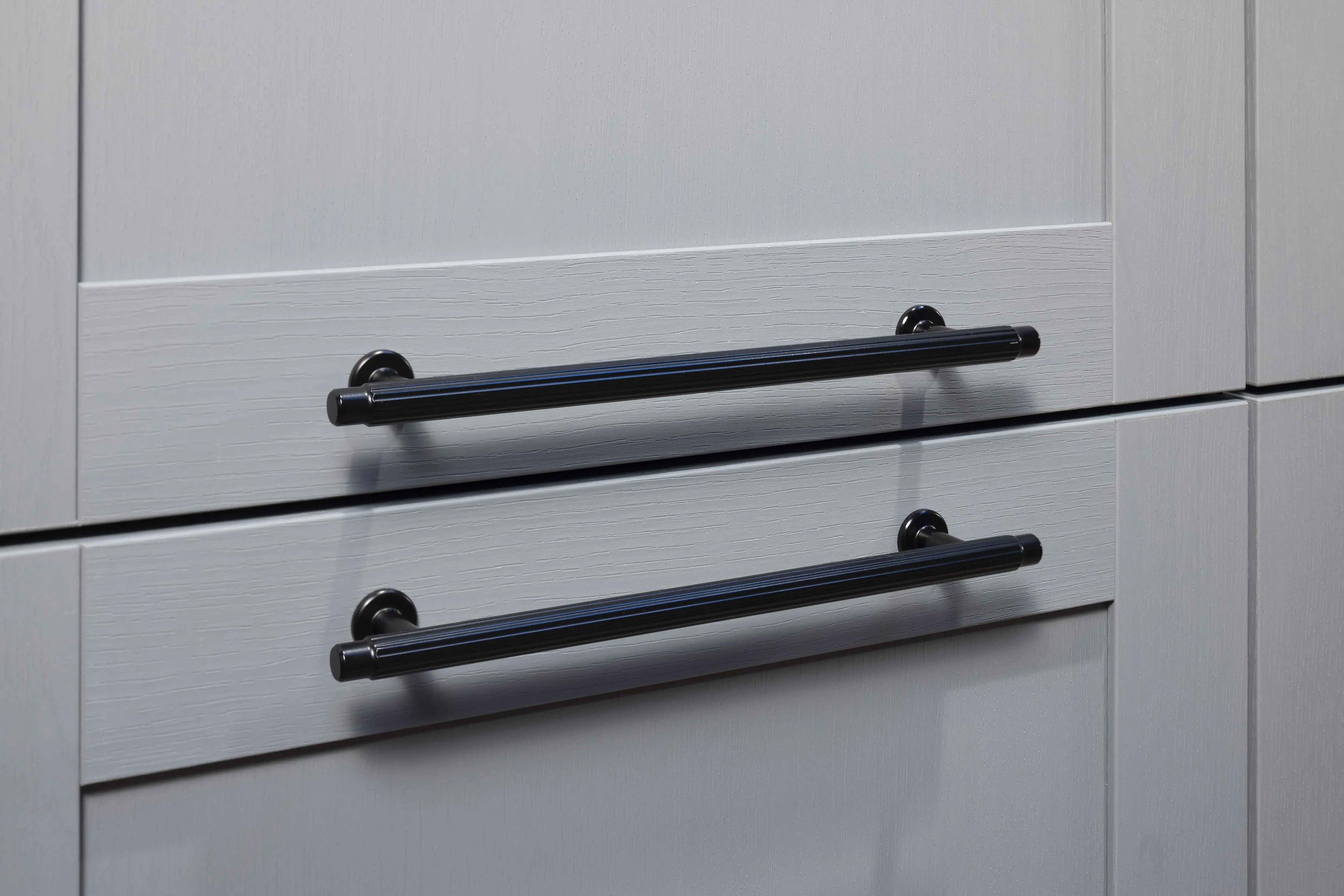 Zwei Schubladen mit schwarzen Griffen an steinblauem Schrank.