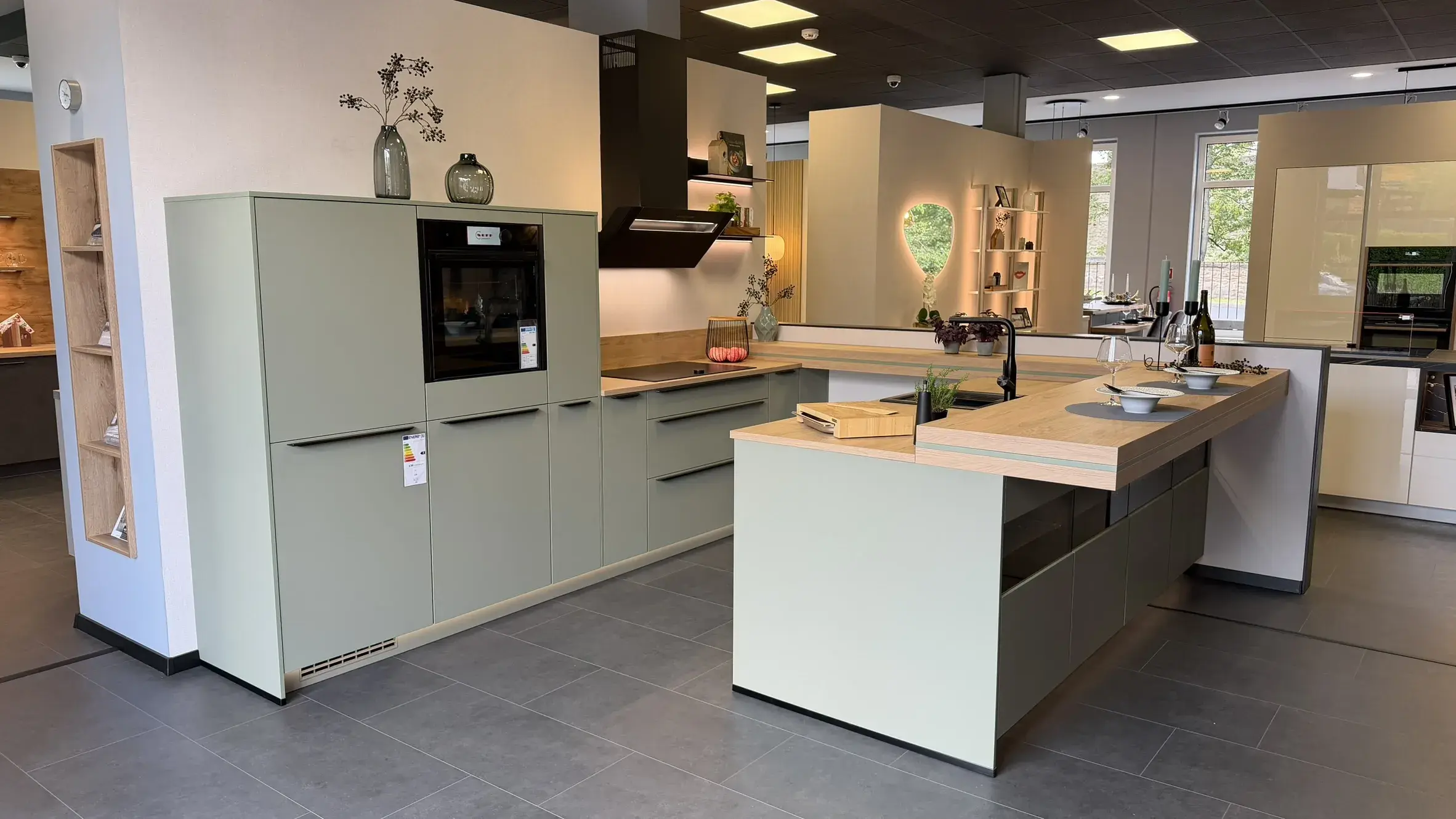 Moderne Küche in Salbeigrün mit Holzarbeitsplatte, Kochinsel und integriertem Essbereich
