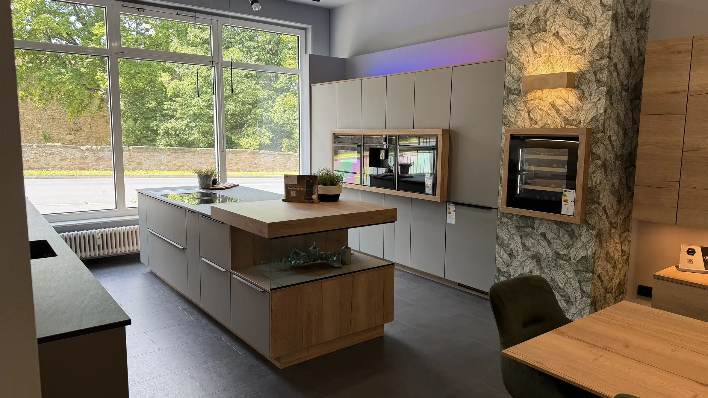 Moderne Designküche mit großer Kochinsel, grauen Fronten, natürlichen Holzelementen und integrierten Küchengeräten