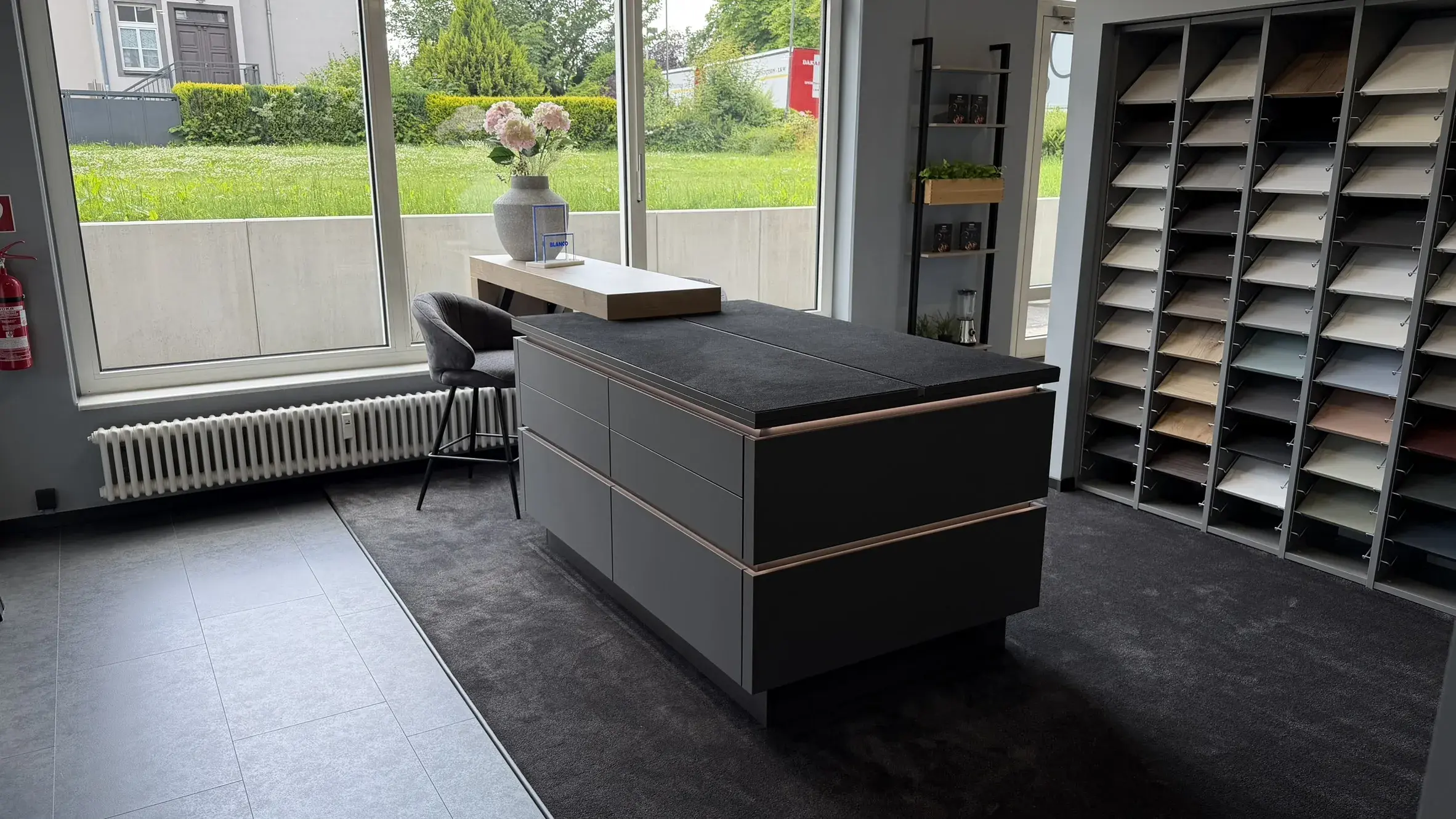 Moderner Bemusterungsbereich im Küchenstudio mit Kücheninsel und großer Auswahl an Fronten, Farben und Materialien für die individuelle Küchenplanung