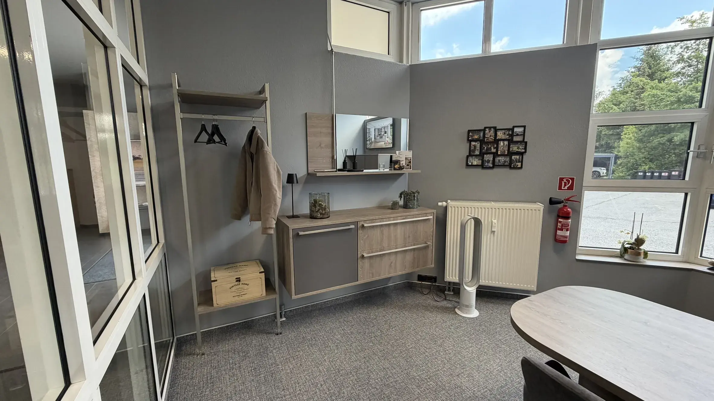 Moderner Eingangsbereich mit Garderobe, wandhängendem Sideboard, Spiegel und großen Fenstern